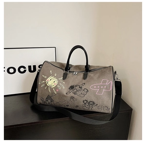 Close-up of large grey travel bag featuring colorful graffiti prints and leather handles