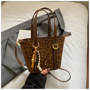 Dettaglio borsa shopper leopardata con logo dorato, ciondolo e tracolla marrone