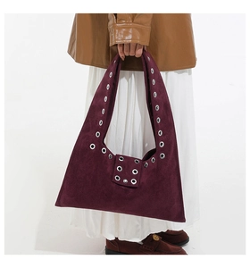 Détail du sac cabas en daim bordeaux avec œillets métalliques argentés et style industriel