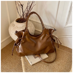 Close-up of dark brown tote bag showing supple pleated texture and versatile strap