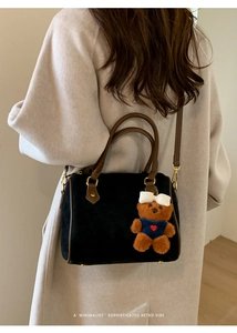 Detail of retro black suede pillow bag with brown leather trim and cute bear charm accent