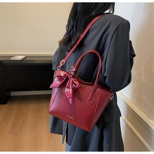 Detailansicht der roten Ledertasche mit elegantem Seidentuch und goldenem Logo
