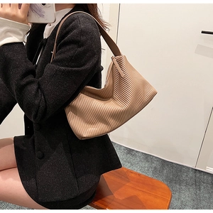Close-up of the pleated texture and curved design of this brown faux leather tote bag