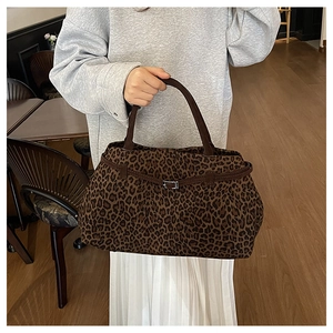 Detalle del bolso tote de ante con estampado de leopardo y asas marrones con hebilla