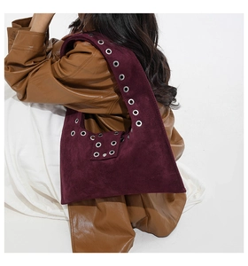 Gros plan sur un sac cabas en daim violet foncé avec des œillets métalliques sur l'épaule