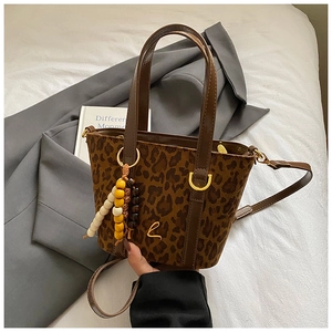 Dettaglio della borsa tote in pelle scamosciata leopardata con ciondolo e finiture dorate