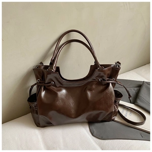 Detailed view of dark brown oil wax leather tote bag with side drawstring and straps