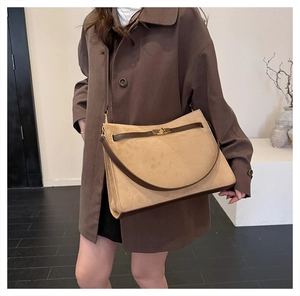 Close-up of vintage suede shoulder bag with brown leather trim and golden metal clasp