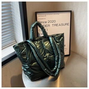 Detail of dark green quilted down tote bag with metallic finish on a round table