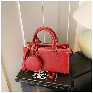 Detail of red pleated leather handbag with small round purse and gold hardware accents