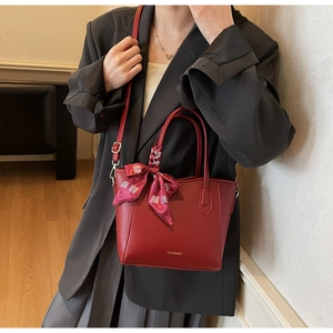 Nahaufnahme der roten Ledertasche mit SOLAR&MISS Logo und dekorativem rotem Blumenseidenschal