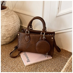 Detail of dark brown vintage Boston bag with leather texture and small round purse charm