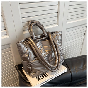 Macro view of metallic silver quilted tote bag texture and padded handle on book