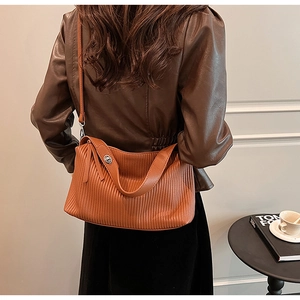 Detail view of brown pleated faux leather shoulder bag with a soft semicircular silhouette