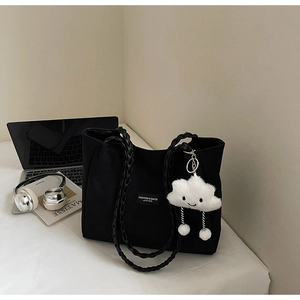 Black large tote bag detail with woven straps and cloud charm on a desktop setting