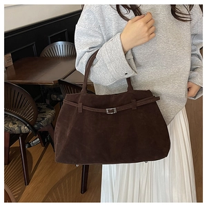 Detalle del bolso tote de ante marrón oscuro con hebilla metálica y acabado mate