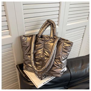 Detail of silver metallic quilted puffer tote bag with thick handles and glossy fabric