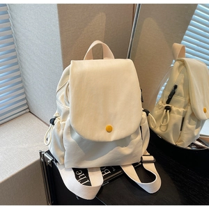 Detailed side view of off-white canvas backpack showing side drawstring pocket and yellow button
