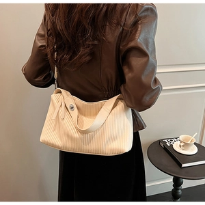 Close-up of vintage beige pleated tote bag featuring a metallic silver twist lock closure