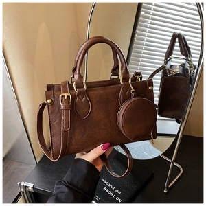Detail of vintage dark brown faux leather handbag with golden hardware and mini pouch