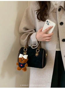 Detail of mini black velvet Boston bag with brown leather handles and teddy bear charm
