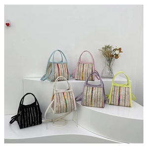 Vista de detalle de seis bolsos tipo cubo tejidos con rayas de colores pastel en vitrina