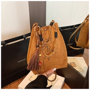 Détail du sac seau en daim marron avec broderie nœud et pompons décoratifs élégants