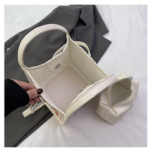 Vista superior de un bolso cuadrado blanco crema con un neceser interior a juego con cremallera
