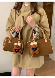 Macro shot of brown suede Boston bag with leather handles and cute bear charm details