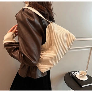 Detailed close-up of beige corduroy shoulder bag with vertical texture and wide strap