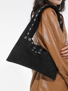 Grand sac à bandoulière en daim noir avec œillets argentés porté par un modèle