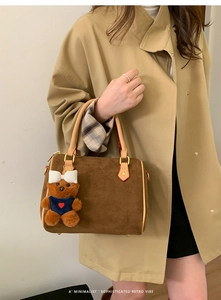 Detailed view of brown matte pillow bag with plush bear charm and golden hardware detail