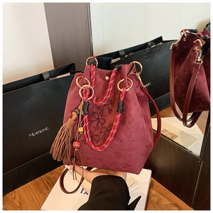 Détail du sac seau en daim bordeaux avec nœud en strass et poignée tissée main