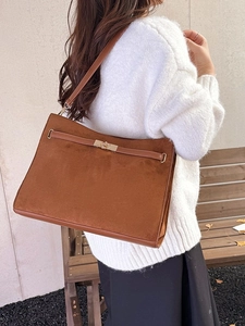 Retro brown suede tote bag with golden lock closure shown in an autumn outdoor setting