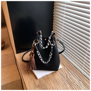 Détail du sac seau noir avec poignées tissées en pied-de-poule et breloque gland