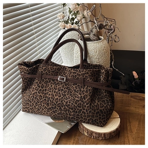 Primer plano detallado del bolso tote de leopardo con asas marrones y hebilla metálica