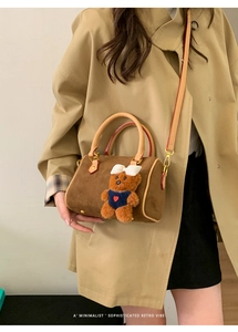 Sophisticated retro cylinder bag with plush bear charm styled on a trench coat