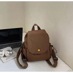 Detailed view of brown canvas backpack with flap closure and yellow button detail