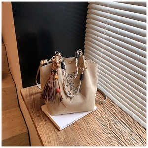 Détail du sac seau abricot avec pompon, perles en bois et poignée en corde tressée sur fenêtre