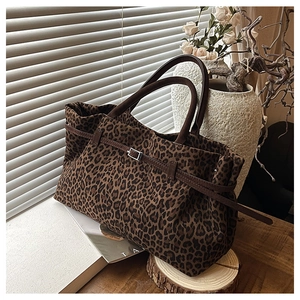 Primer plano del bolso tote de leopardo en ante con asas de cuero y hebilla decorativa