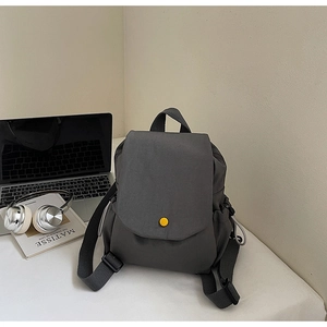 Detail of dark grey canvas backpack with yellow button and laptop workspace items
