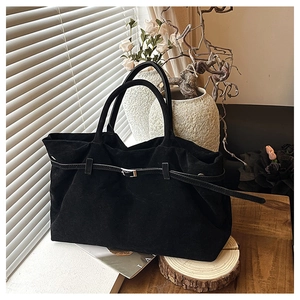 Detalle del bolso tote de ante negro con una hebilla cuadrada plateada decorativa