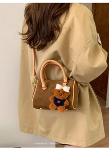 Detail of dark brown suede boston bag featuring a cute plush bear charm accessory