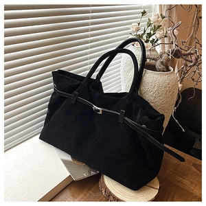 Detalle del bolso tote de ante negro con cinturón de hebilla y diseño de pliegues suaves