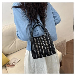 Detalle del bolso tote de rayas tejidas de colores con asa de cuero y textura tweed