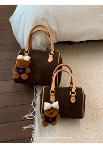 Close-up of retro brown frosted leather boston bag with cute bear charm and golden zipper