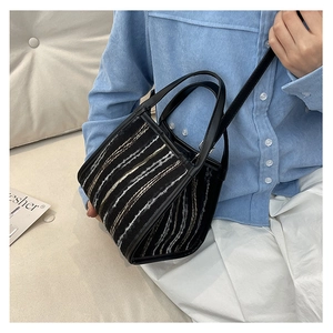 Detalle del bolso de cubo negro a rayas con textura de tweed y asas de cuero fino