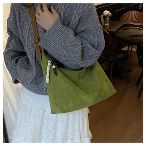 Détail du sac cabas en daim vert avec bandoulière en cuir et gland à perles
