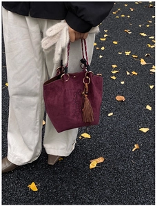 Détail du cabas en daim bordeaux avec broderie nœud et pompon sur des feuilles d'automne