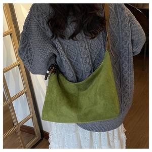 Gros plan détaillé du sac cabas en daim vert herbe avec perles en bois et bandoulière en cuir